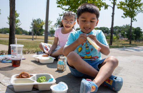 two children eat lunch outside